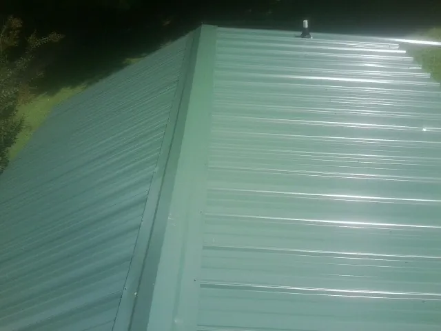 New green metal panels meeting at the ridge of a roof — Flat Roof Repair work by our crew in Agness