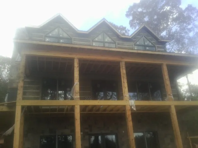 Dormers and porch framing on a large log home under construction — Roof Coating work by our crew in Agness