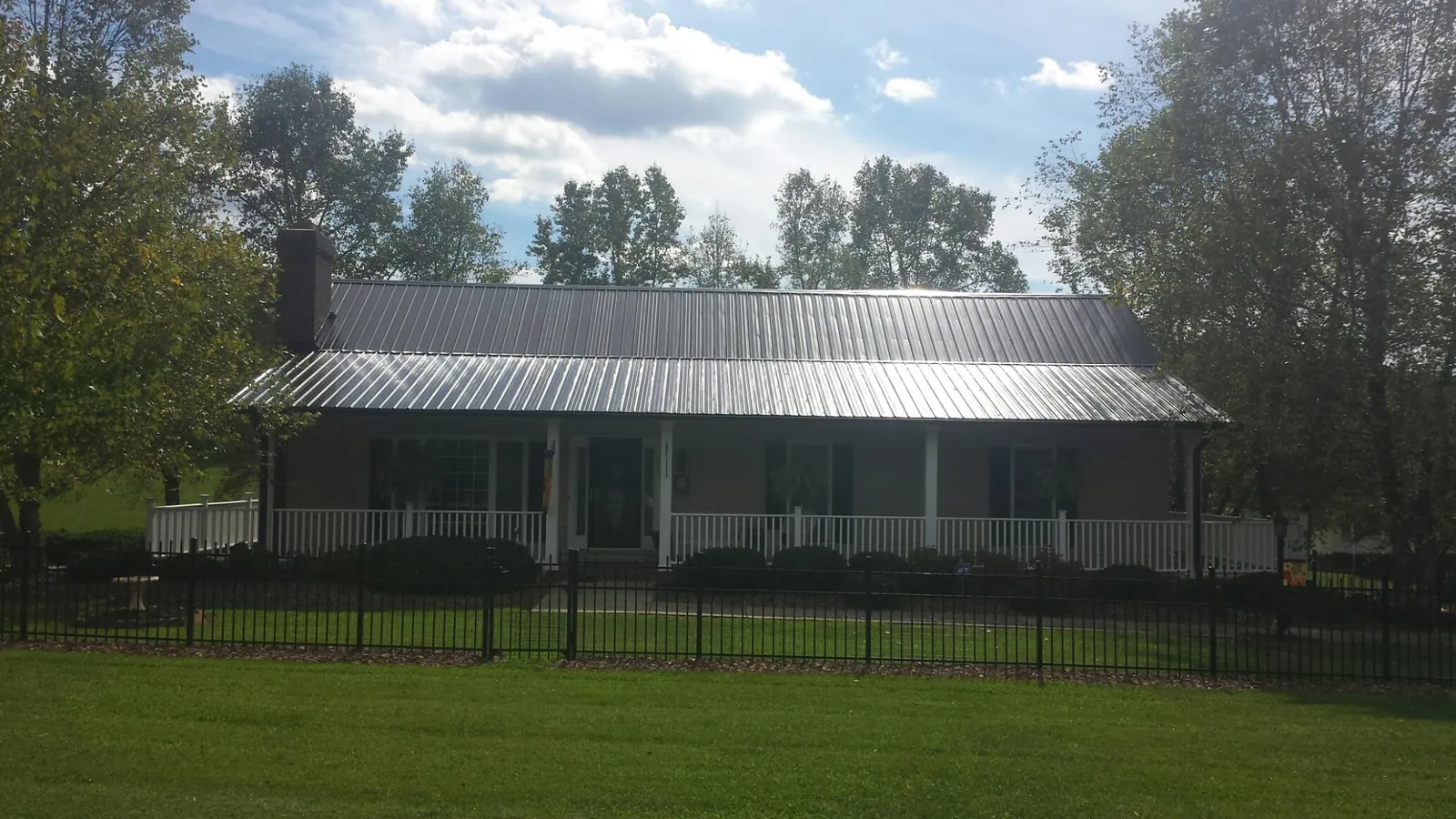 Gray metal roof on a brick ranch with a full width front porch — Gutter Guard Installation work by our crew in Agness