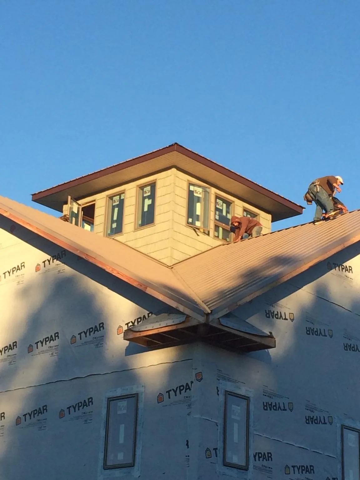 Roofers working around a rooftop cupola on a new metal roof at sunset — Roof Waterproofing in Agness by Roofing Brothers